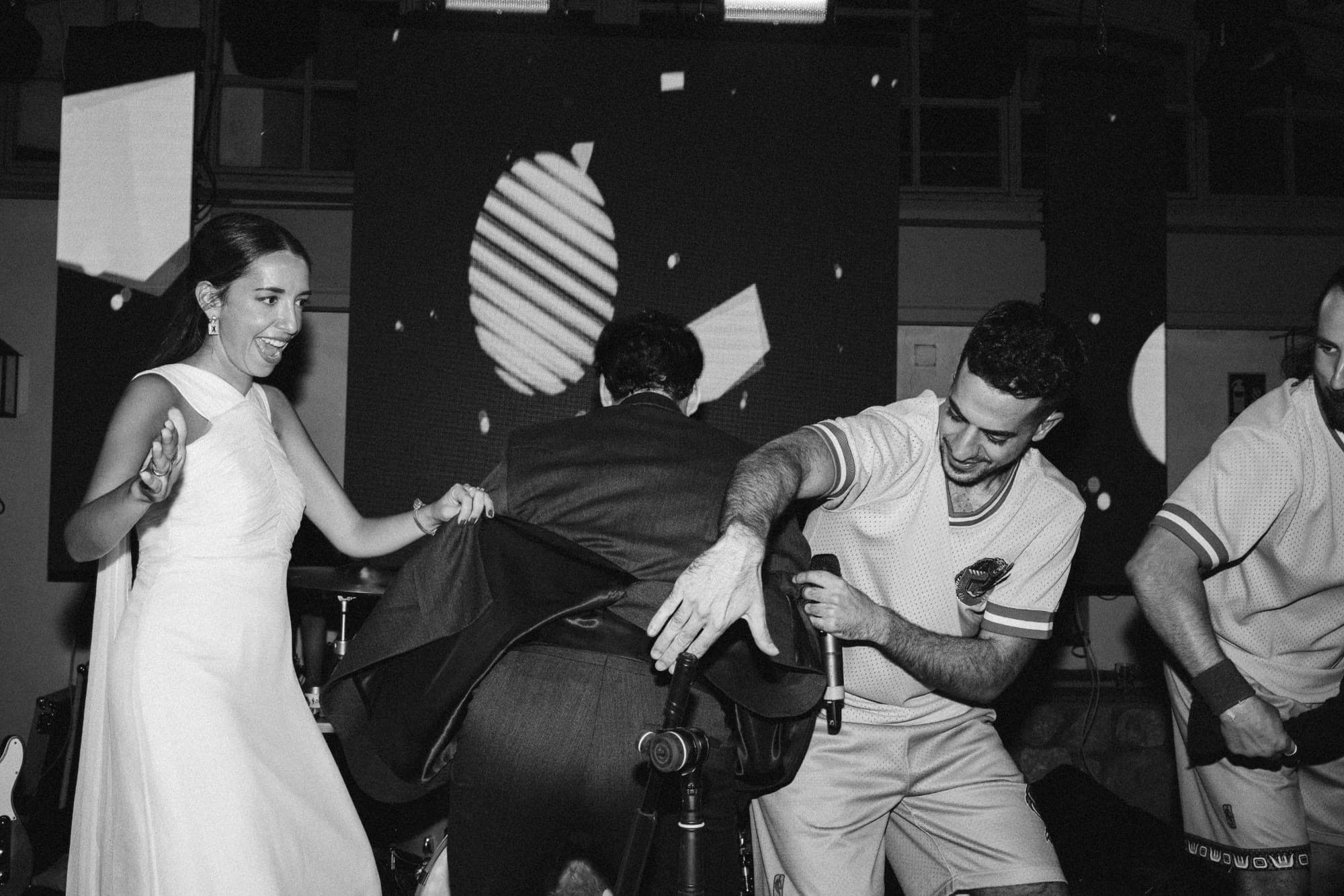 La novia ríe a carcajadas en el escenario mientras el cantante bromea con el novio