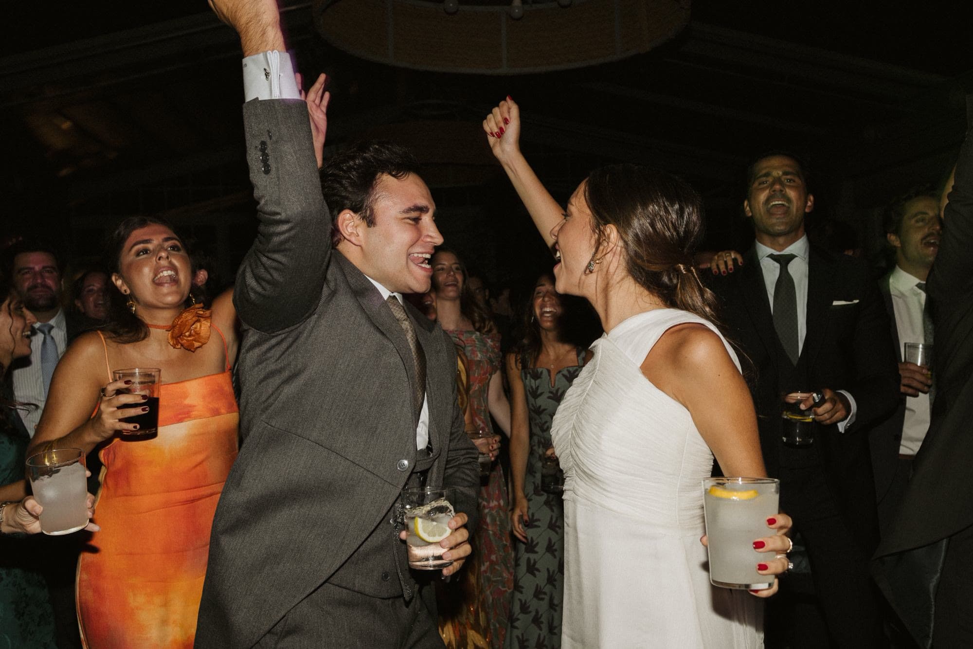 Novios e invitados bailando con copas en la barra libre de una boda